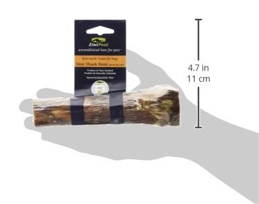 Half a deer shank bone held up by an outline of a hand to give a reference of its size. Produced by Ziwipeak for dogs' oral health
