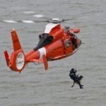 US Coast Guard Helicopter with a man suspended saving a dog
