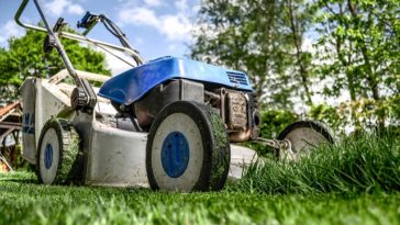 A Lawnmower on a lawn mowing grass on someones yard