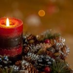 Photo of a candle with Christmas decorations. Article about actives to do if you are alone on Christmas