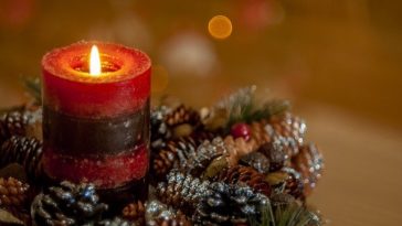 Photo of a candle with Christmas decorations. Article about actives to do if you are alone on Christmas