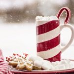 Snowing in the background. Hot beverage in front with cookies. Christmas scene. Everything in red and white, Christmas colors.